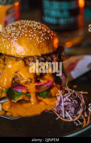 Eine vertikale Aufnahme eines Chicken Burgers in einem dunklen, grungigen Restaurant Stockfoto