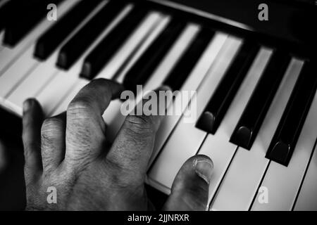 Eine Nahaufnahme einer Hand, die Klavier spielt, in Graustufen Stockfoto