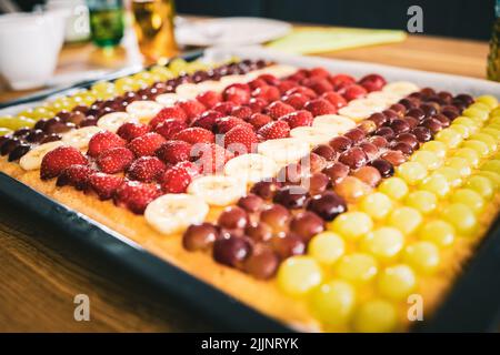 Eine Nahaufnahme einer Auswahl von geschnittenen Früchten wie Erdbeeren und Bananen auf dem schwarzen Tablett Stockfoto