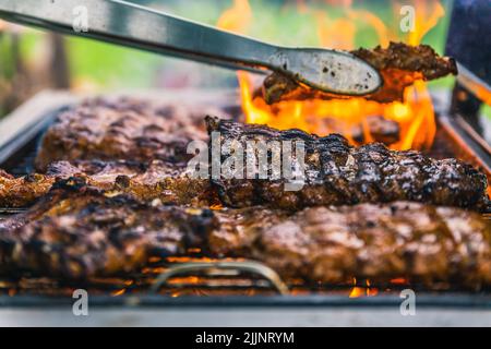 Eine Nahaufnahme des Prozesses der Zubereitung von köstlichen gegrillten Steaks auf dem Feuer im Freien Stockfoto