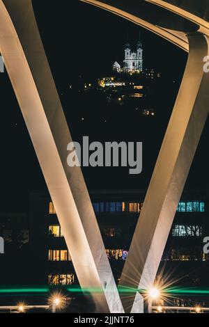 Eine vertikale Fernansicht der Postlingberg-Wallfahrtskirche, aufgenommen von einer nächtlichen Brücke in Linz, Österreich Stockfoto