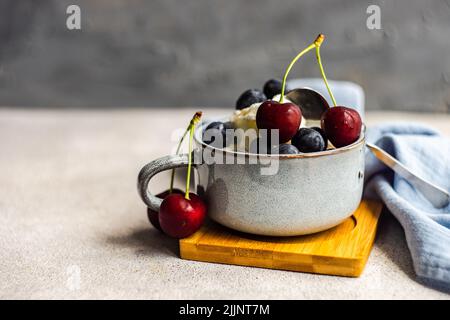 Nahaufnahme von Vanilleeis mit frischen Heidelbeeren und Kirschen Stockfoto
