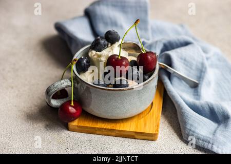 Nahaufnahme von Vanilleeis mit frischen Heidelbeeren und Kirschen Stockfoto
