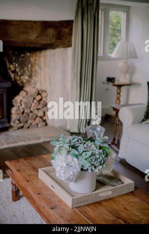 Eine vertikale Aufnahme einer Wohnzimmereinrichtung im Tudor-Haus mit Orchideen und einem Kamin, Chippenham, Großbritannien Stockfoto