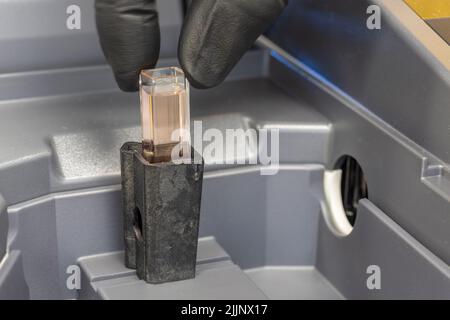 Küvette mit einer Probe, die in ein Spektralfotometer eingelegt wird. Stockfoto