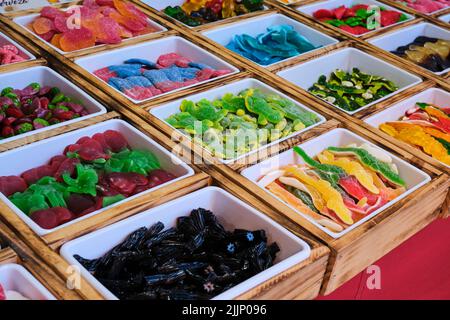 Hoher Winkel verschiedener süßer Gelee-Bonbons in Kunststoffbehältern, die auf einem Stall im Süßwarengeschäft platziert werden Stockfoto