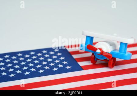 Das Spielzeugflugzeug steht auf der US-Flagge. Reise- und Geschäftskonzept Stockfoto