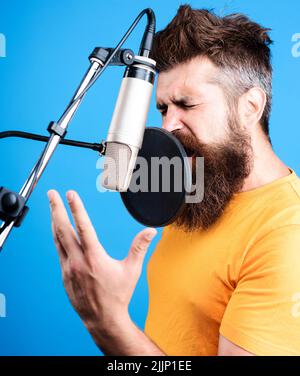 Männlicher Sänger, der im Kondensatormikrofon singt. Professioneller Sänger im Studio. Musik, Freizeitkonzept. Stockfoto