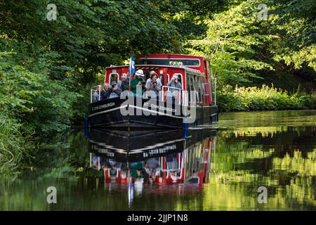 Schottland, Vereinigtes Königreich, 27.. Juli 2022. UK Wetter: Sonniger Abend auf dem Union Canal. Eine Fotografiegruppe genießt eine Kreuzfahrt entlang des Kanals in einem schmalen Boot, das sich im Wasser spiegelt Stockfoto