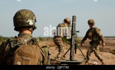 Ein finnischer Soldat, der der Pori-Brigade zugewiesen ist, beobachtet US-Soldaten, die 4. Squadron, 10. Kavallerieregiment, 3. Panzerbrigade-Kampfteam, 4. Infanterie-Division zugeordnet sind, die sich darauf vorbereiten, das Mörsersystem M120 120mm während einer gemeinsamen Mörserübung in Niinisalo, Finnland, am 21. Juli 2022 abzufeuern. Die 3. ABCT, 4. ID und die Pori Brigade begannen mit Sommertrainings in Finnland, um die Beziehungen zu stärken und die Interoperabilität zwischen den beiden Nationen zu fördern. Die 3. ABCT ist unter anderem der 1. Infantry Division zugeordnet, die unter dem Kommando und der Kontrolle des V Corps steht, dem amerikanischen Vorwärtskorps in Europa Stockfoto