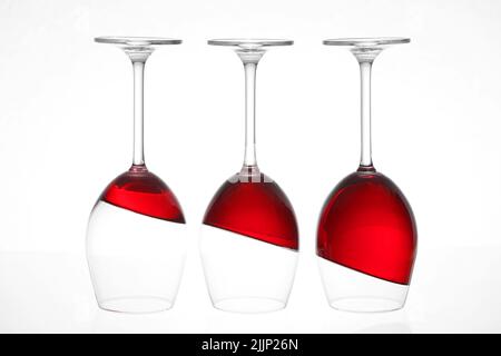 Drei umgekehrte Weingläser mit Rotwein isoliert auf weißem Hintergrund Stockfoto