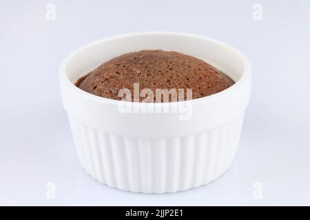 Ein Schokoladensouffle in einem klassischen weißen Porzellan-Ramekin auf weißem Hintergrund Stockfoto