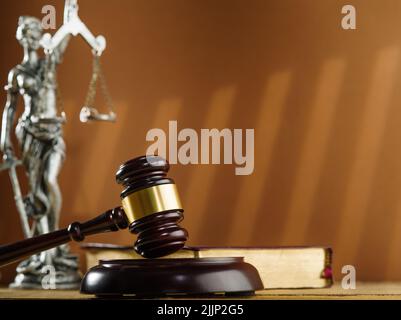 Auf einem beigen Hintergrund sind die Symbole eines fairen Prozesses der Gavel des Richters, eine Bronzestatue von Themis und ein offenes Buch. Verfassung, Bibel, Strafgesetzbuch Stockfoto