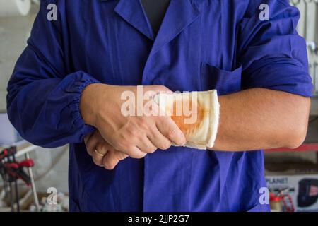 Bild eines Handwerkers mit einer verbundenen Wunde am Arm. Verweis auf Arbeitsunfälle Stockfoto