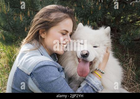 Junge schöne Frau Porträt mit ihrem flauschigen und glücklichen Hund samoyed Stockfoto
