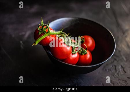 Schüssel mit frischen Kirschtomaten auf der Weinrebe Stockfoto