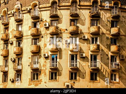 Abgerundete Balkone auf abgerundeten Gebäude in Tiflis Georgia Eurasia mit abblätterndem Gips und Klimaanlage, die ein strukturiertes Muster bilden. Stockfoto