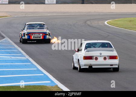 Ein „BMW E9 CSL“ flammender Auspuff, gefolgt von einem „E30 M3“ auf dem Donington Park Circuit, Leicestershire, Großbritannien Stockfoto