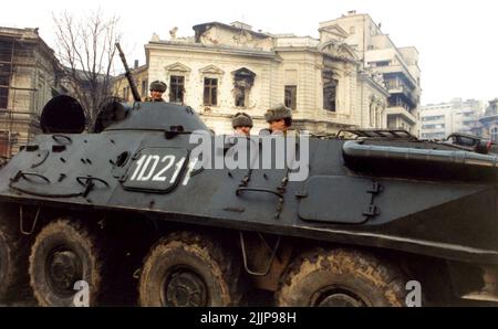 Bukarest, Rumänien, Januar 1990. Armee in Piata Palatului/Piata Revolutiei, vor einem historischen Gebäude, das während der antikommunistischen Revolution in Rumänien im Dezember 1989 durch Schüsse zerstört wurde. Stockfoto