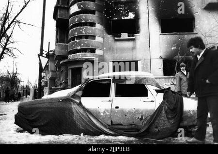 Bukarest, Rumänien, Januar 1990. Wohngebäude im historischen Zentrum und Fahrzeug durch den Schusswechsel während der antikommunistischen Revolution in Rumänien im Dezember 1989 verschlechtert. Stockfoto