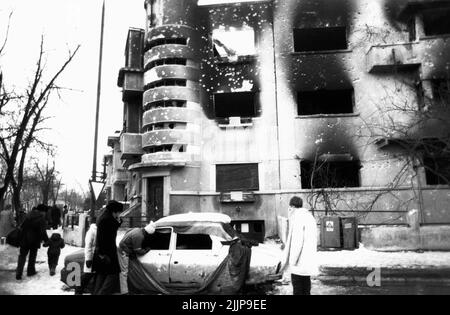 Bukarest, Rumänien, Januar 1990. Wohngebäude im historischen Zentrum und Fahrzeug durch den Schusswechsel während der antikommunistischen Revolution in Rumänien im Dezember 1989 verschlechtert. Stockfoto