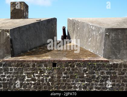 Nahaufnahme eines Kanons zwischen einer schmalen Barriere an einer Ziegelwand Stockfoto