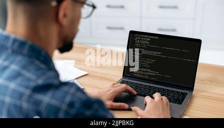 IT-Technologie. Panoramafoto eines Programmierers mit Laptop. Blick über die Schulter eines Mannes, eines IT-Spezialisten auf einen Laptop-Bildschirm, ein männlicher Programmierer schreibt Codes für eine Anwendung vor, entwickelt Software Stockfoto