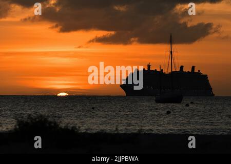 Silhouette einer Yacht gegen einen schönen orangefarbenen Sonnenuntergang Stockfoto