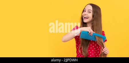 Happy Kid Kämmen lange Haare. Friseur. Mädchen hat wellige Frisur halten Haarbürste. Teen Schönheit Frisur. Kid girl Haarpflege, horizontales Poster. Banner Stockfoto