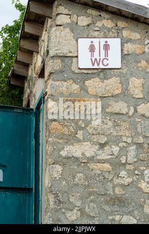 Schild alte Herz WC Tür Stein im Freien Holz Hintergrund Bad, für latrine Design aus primitive für wc-Anlage, schönes Zuhause. Europa Stockfoto