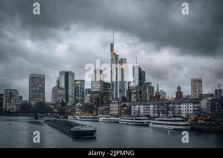 Ein malerischer Blick auf die Frankfurter Stadt mit ihren Wolkenkratzern und Yachten an einem dunklen, düsteren Tag Stockfoto