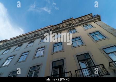 Eine Aufnahme aus einem niedrigen Winkel eines alten Gelbbaues und eines Gebäudes gegen den blau-bewölkten Himmel Stockfoto