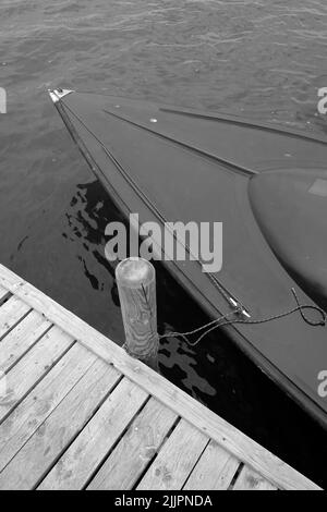 Ein Boot, das auf einem Holzpfosten in einem Dock festgebunden ist Stockfoto