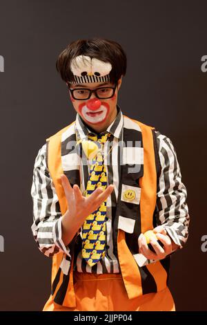 Ein männlicher Clown jongliert auf der Geburtstagsfeier mit Bällen Stockfoto
