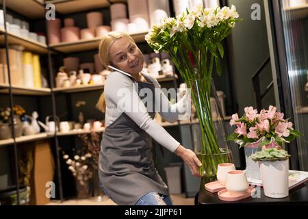 Der Florist nimmt eine Bestellung per Telefon sammeln Blumensträuße von natürlichen Blumen Stockfoto