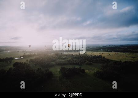 Eine Luftaufnahme von Luftballons in der Luft über einem Tal bei Sonnenaufgang, Stockfoto