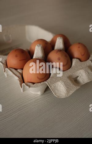 Eine vertikale Aufnahme von Eiern mit gemalten Emotionen in einem Eierkarton Stockfoto