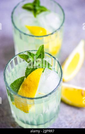 Nahaufnahme von zwei Mojito-Cocktails auf einem Tisch mit frischer Minze und Zitrone Stockfoto