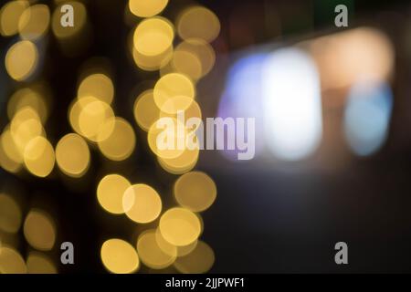 Verschwommene dekorative Außenleuchten am Baum im Garten bei Nacht. Bokeh. Weihnachtslicht auf Baum. Für Hintergrund und Gestaltung Stockfoto