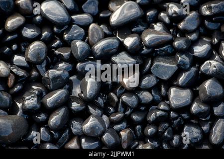 Nahaufnahme von schwarzen vulkanischen Kieselsteinen am Strand von Mavra Volia auf der Insel Chios in Griechenland. Stockfoto