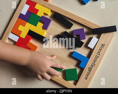 Eine Draufsicht auf ein Block-Puzzle mit bunten Stücken und einer Kinderhand, die für Fähigkeiten und Bildung spielt Stockfoto