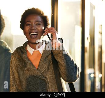 Die Sonne ist wieder draußen, wollen zu Mittag essen. Eine junge Geschäftsfrau mit einem Smartphone, während sie an einem regnerischen Tag in der Stadt spazieren geht. Stockfoto