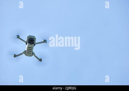 Ottawa, Ontario, Kanada - 23. Mai 2022: Eine Quadcopter-Drohne von DJI Mavic Mini wird von unten gesehen, während sie vor einem klaren, blauen Himmel fliegt. Stockfoto