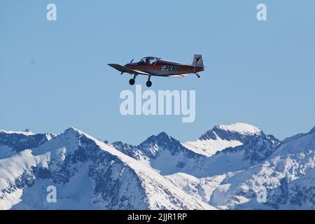 Ein Flugzeug, das über die verschneiten Berge fliegt Stockfoto