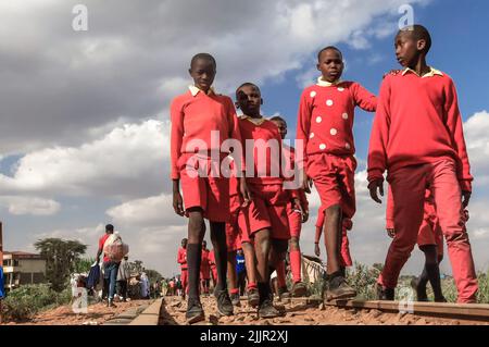 Schüler, die von der Schule durch eine Zuglinie durch das Kibera Slum in Nairobi, Kenia, nach Hause gehen. Leben in Kibera Afrikas größtem Slum. Stockfoto