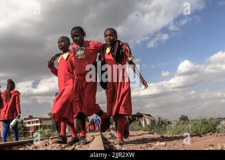 Schüler, die von der Schule durch eine Zuglinie durch das Kibera Slum in Nairobi, Kenia, nach Hause gehen. Leben in Kibera Afrikas größtem Slum. Stockfoto