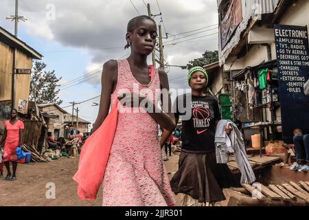 Die Bewohner gehen an den belebten Straßen im Kibera Slum in Nairobi, Kenia, vorbei. Leben in Kibera Afrikas größtem Slum. Stockfoto