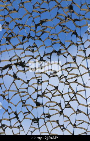 Wunderschöne silberne Linien eines zerschmetterten Fensters erzeugen ein komplexes Muster vor einem tiefblauen Himmel. Stockfoto
