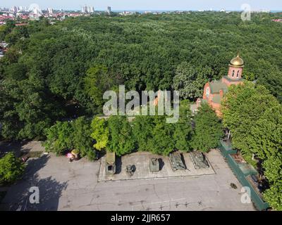 22. Juni 2021, Odessa, Odes'ka Oblast'', Ukraine: (ANMERKUNG DER REDAKTION: Bild aufgenommen mit Drohne) Gesamtansicht der Kirche des Heiligen Großmärtyrers und des siegreichen Georg und militärischer Ausrüstung aus dem Zweiten Weltkrieg. Das Denkmal der heldenhaften Verteidigung Odessas der Küstenbatterie von 411. ist ein Gedenkkomplex, der der heldenhaften Verteidigung Odessas während des Großen Vaterländischen Krieges gewidmet ist. Der Gedenkkomplex umfasst ein Museum, eine Open-Air-Ausstellung mit militärischer Ausrüstung, eine Küstenverteidigungsbatterie und einen großen Park, der mit Eichen bepflanzt ist. (Bild: © Viacheslav Onyshchenko/SOPA Images via ZUMA Press Stockfoto