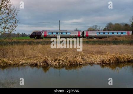 Ein düsterer Tag in Staffordshire, England, mit einem Zug, der an einem kleinen See umherzoomt, der von getrocknetem Gras umgeben ist Stockfoto